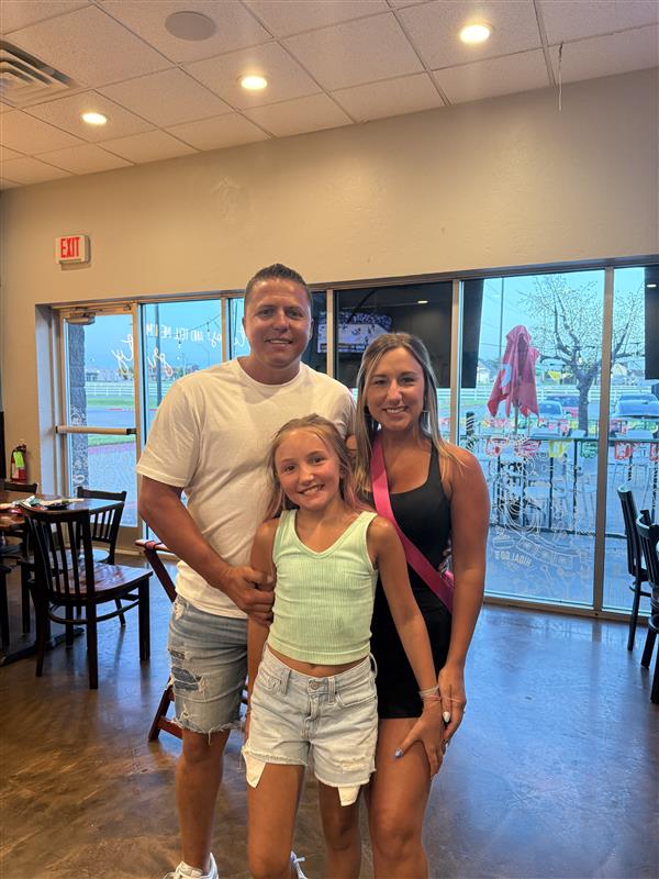 Sara Chairez posing and smiling with her husband and daughter