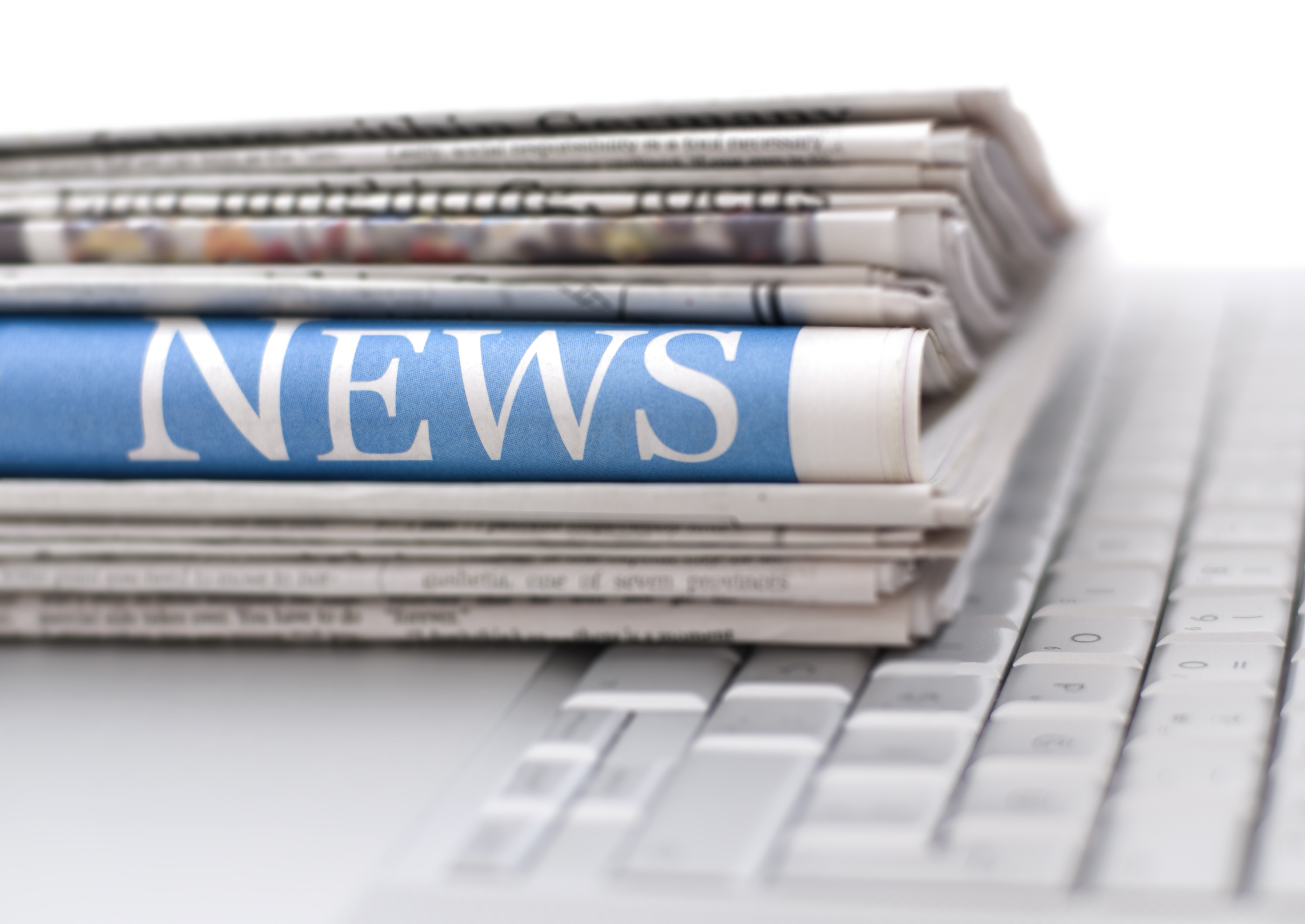 Stack of newspapers on top of a white keyboard
