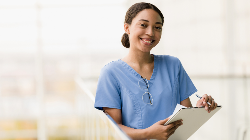 Student nurse smiling while holding a clipboard