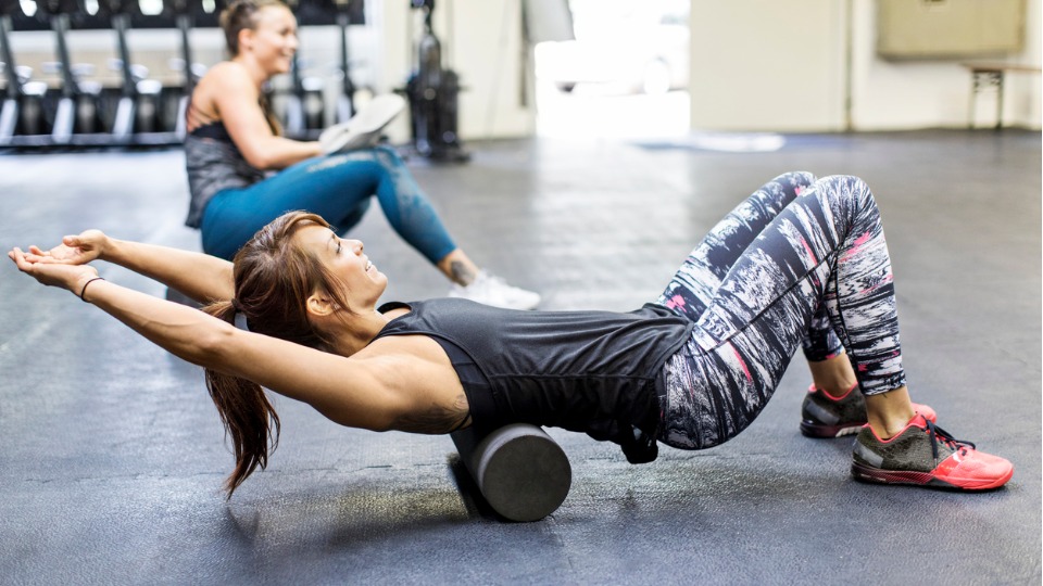 woman exercising on foam roller in gym