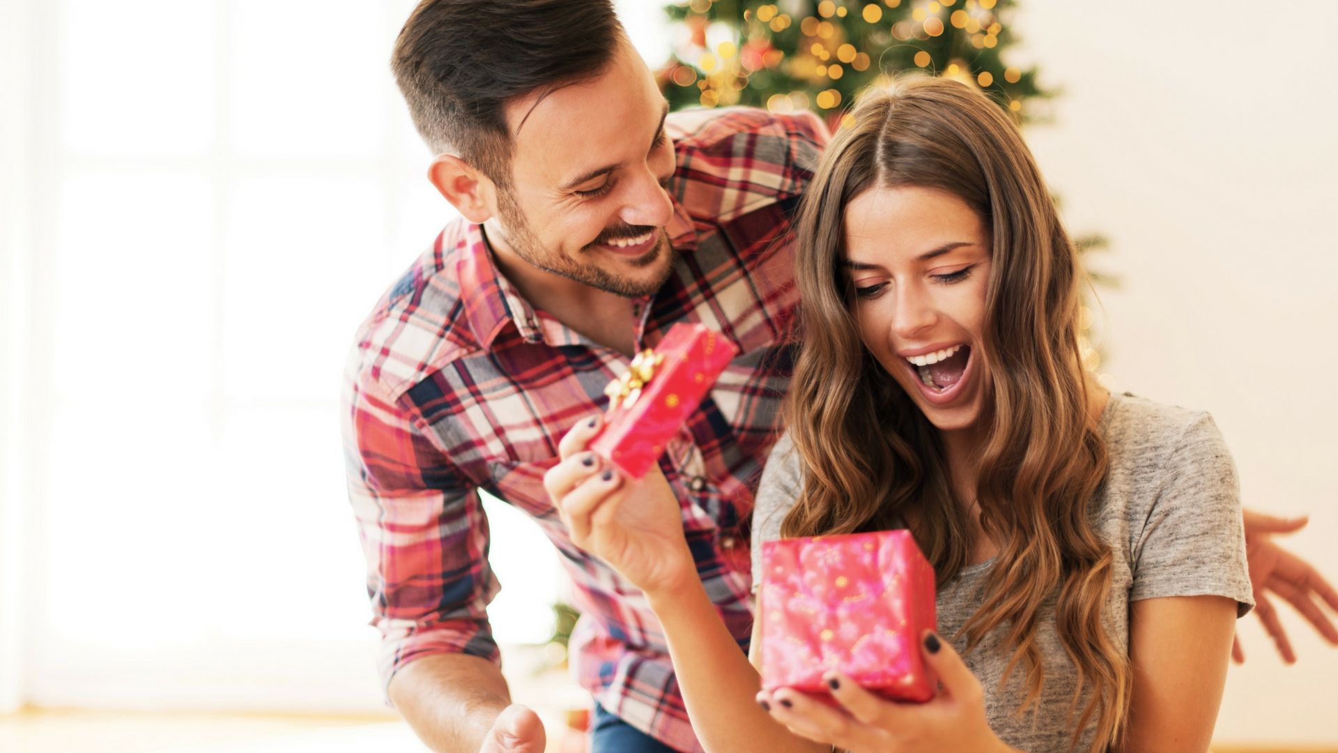 man watching woman open gift