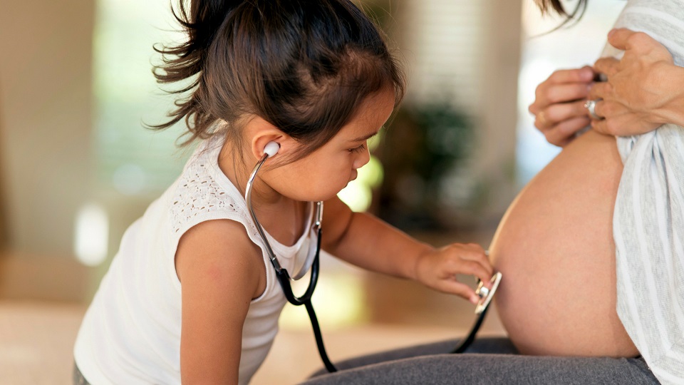 Little girl looking at her mother's pregnant belly