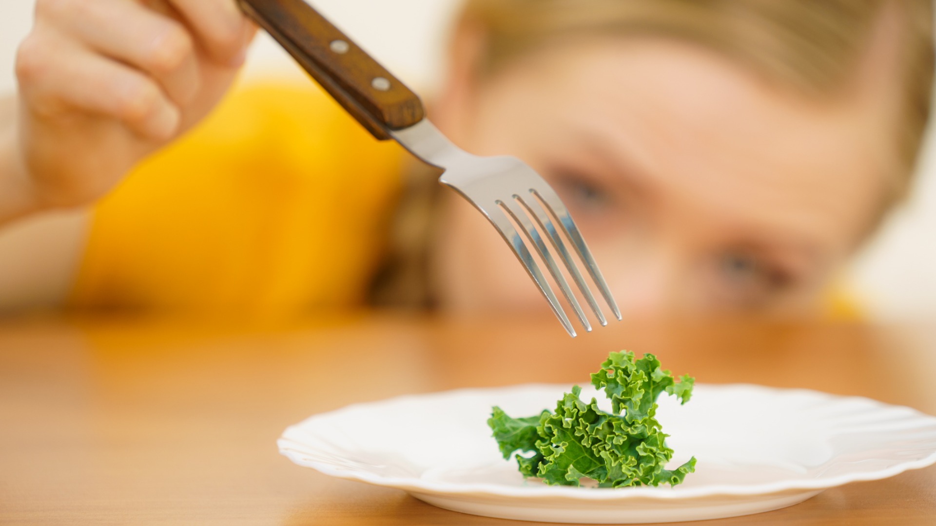 young woman eating a piece of lettuce