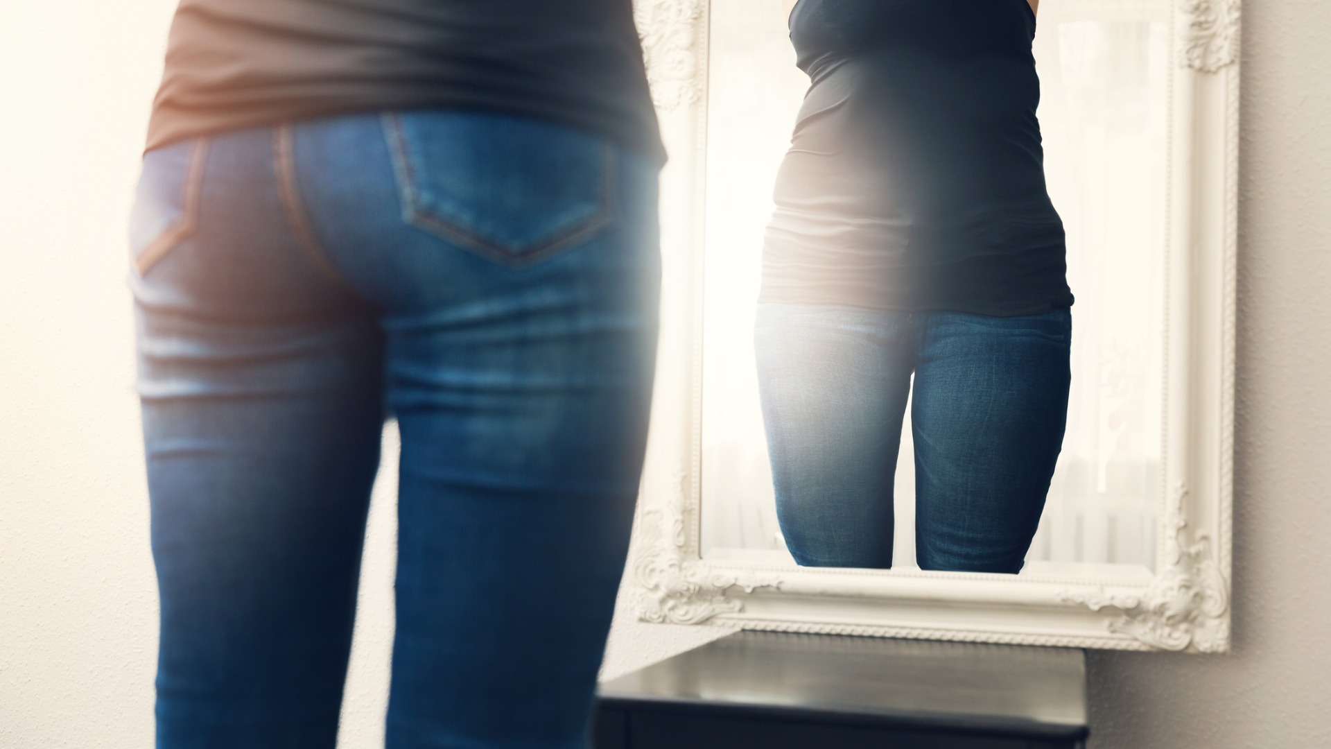 woman who has lost weight likes looking at herself in mirror