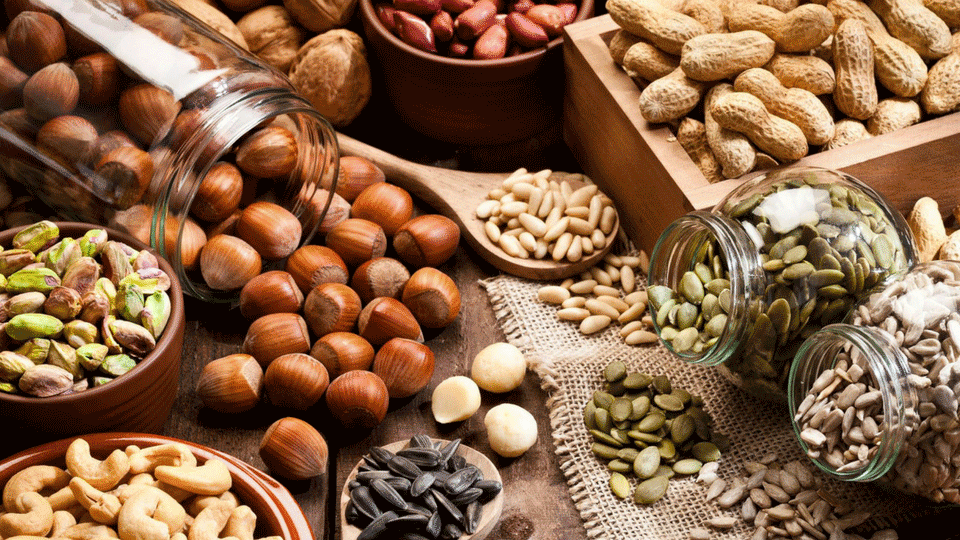 types of nuts and seeds in bowls, jars and spoons