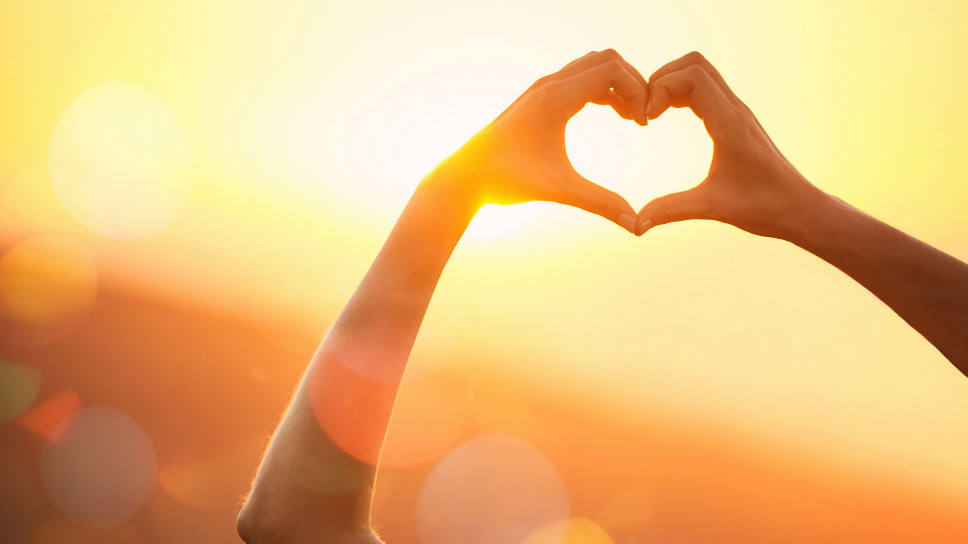 woman in sun making a heart with her fingers