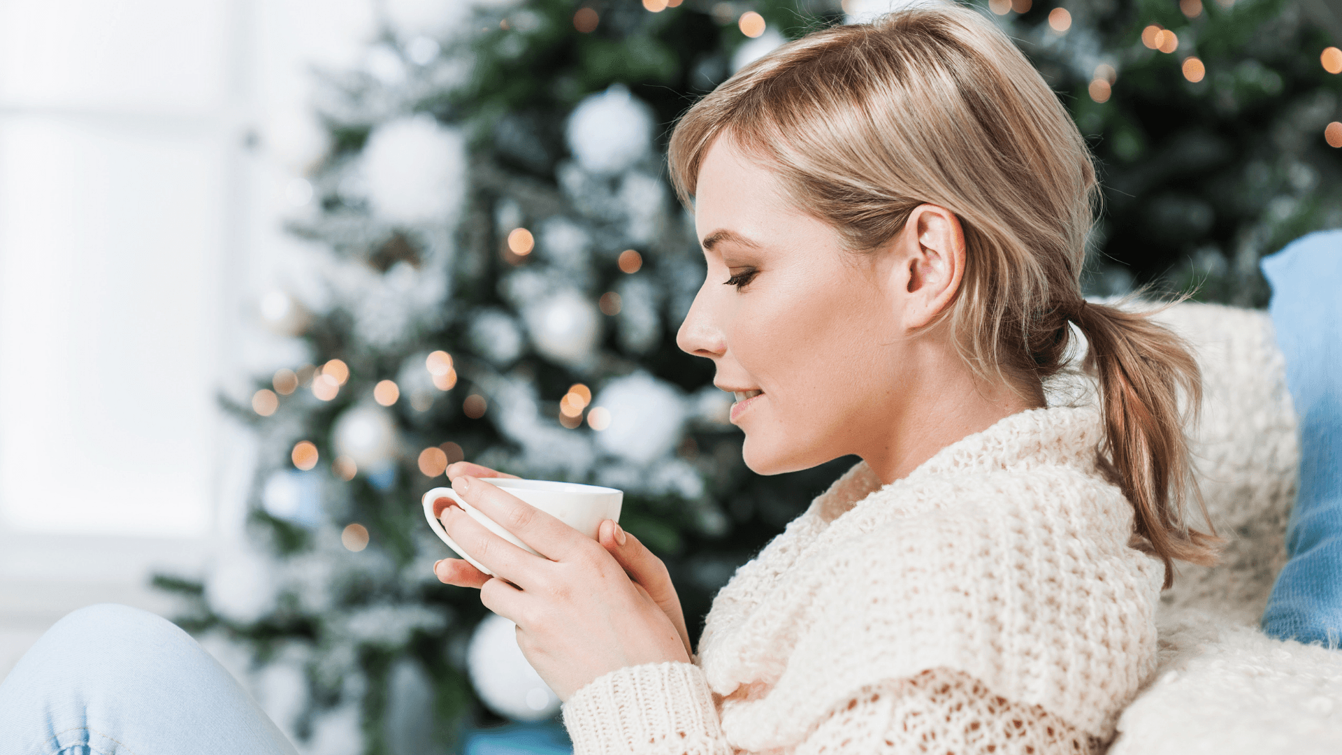 woman drinking tea by christmas tree