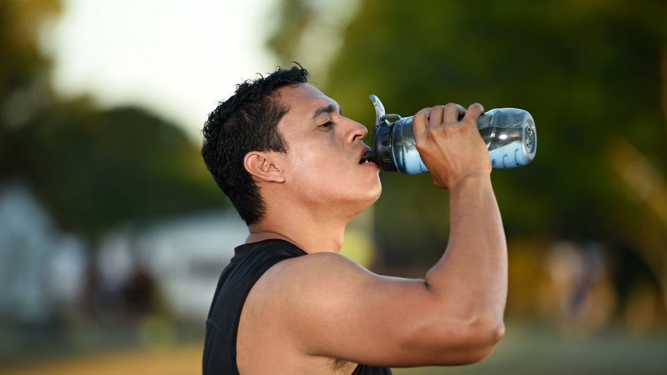 Man drinking water while exercising outside