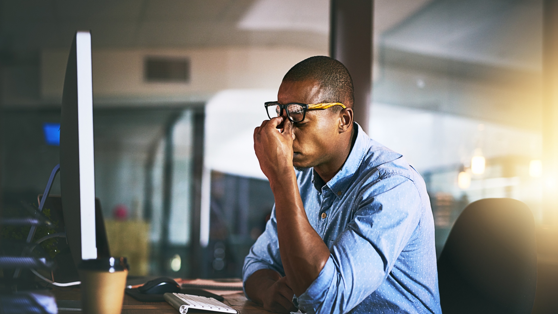 Man sitting at a desk holding his head