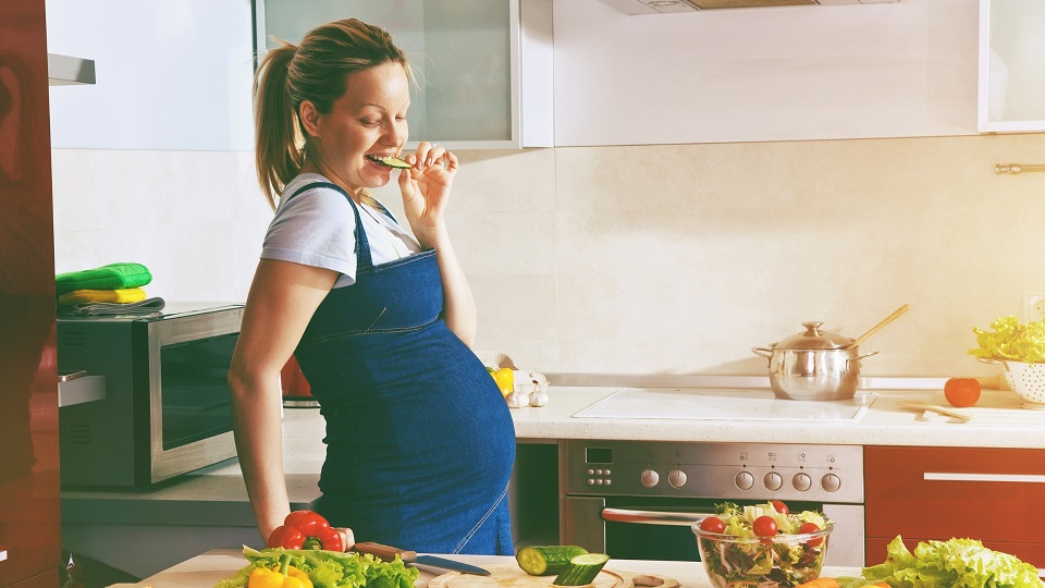 pregnant woman eating a vegetable