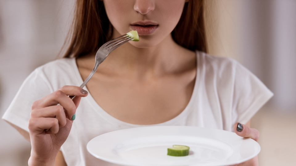 woman eating only a slice of cucumber