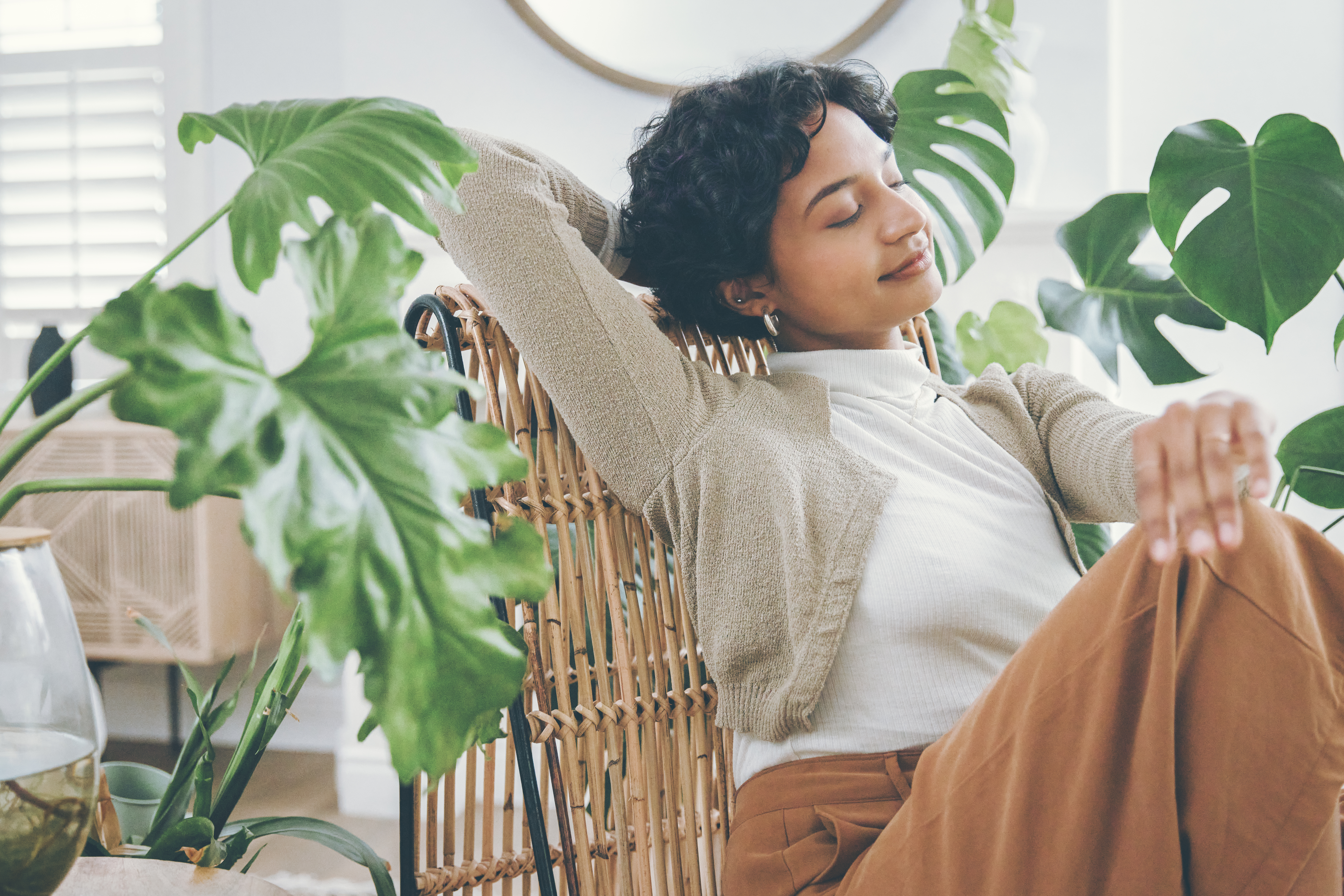a woman relaxes in a chair surrounded by plants