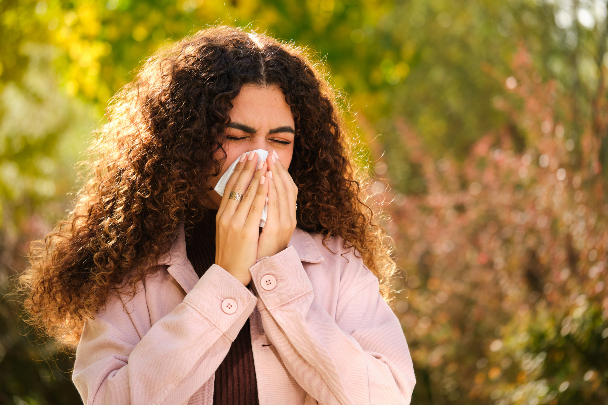 A woman sneezes due to cedar allergies