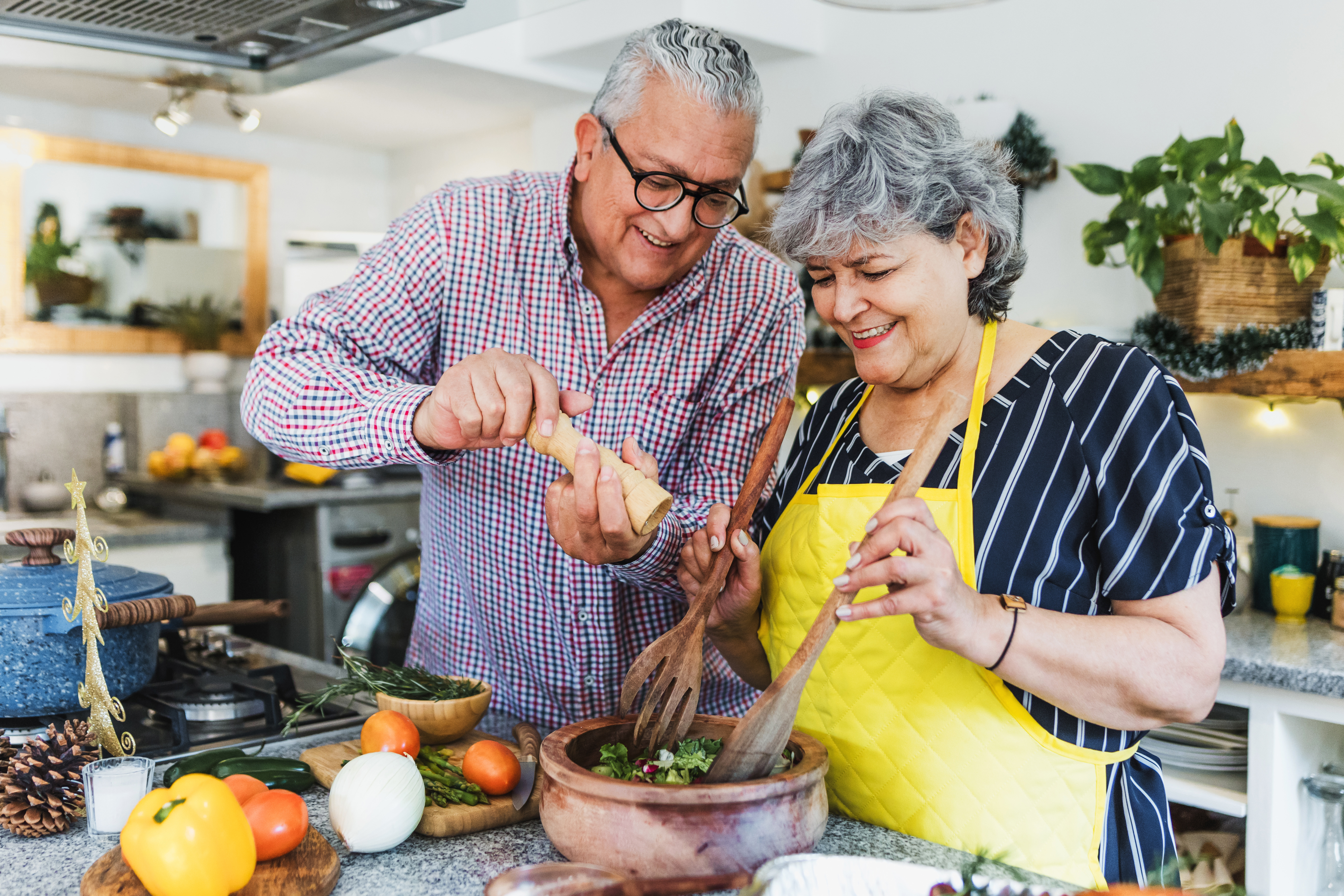 an older couple cooks together and makes a salad 