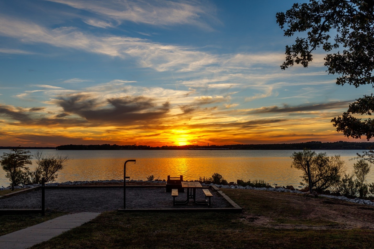 the sun sets over a lake and park