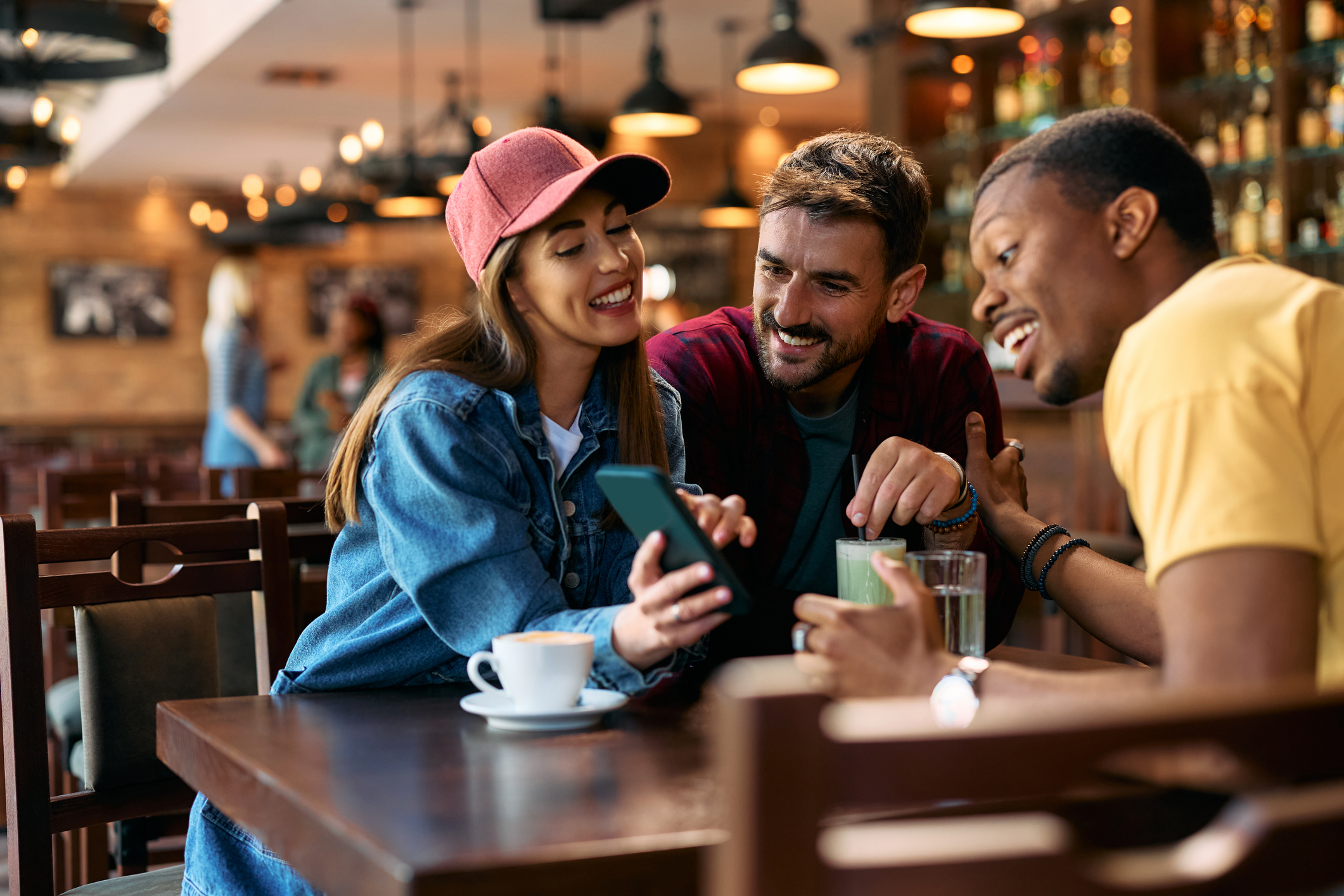 group of young people using app on mobile phone in a bar.