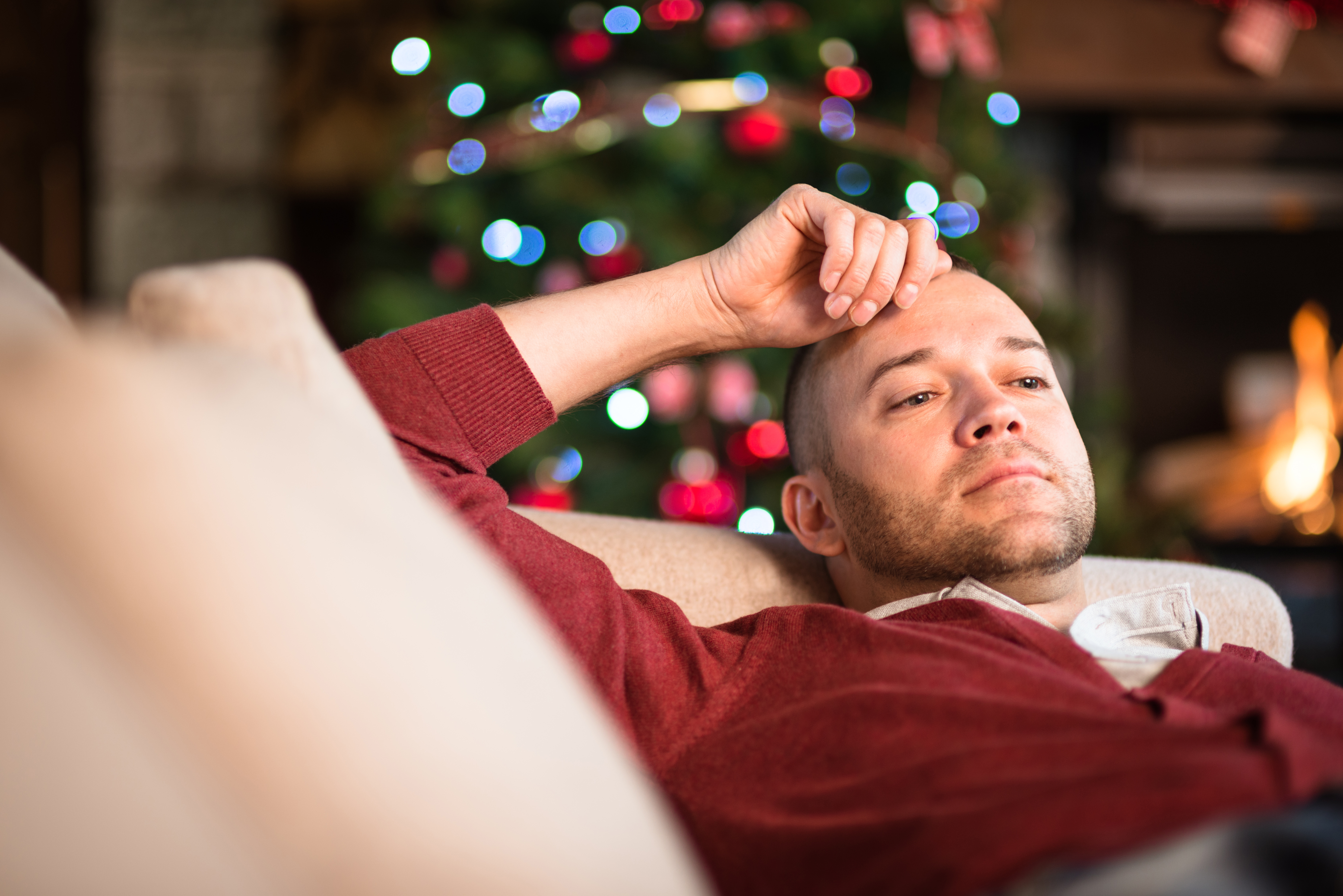 A man contemplates life while sitting in front of a Christmas tree