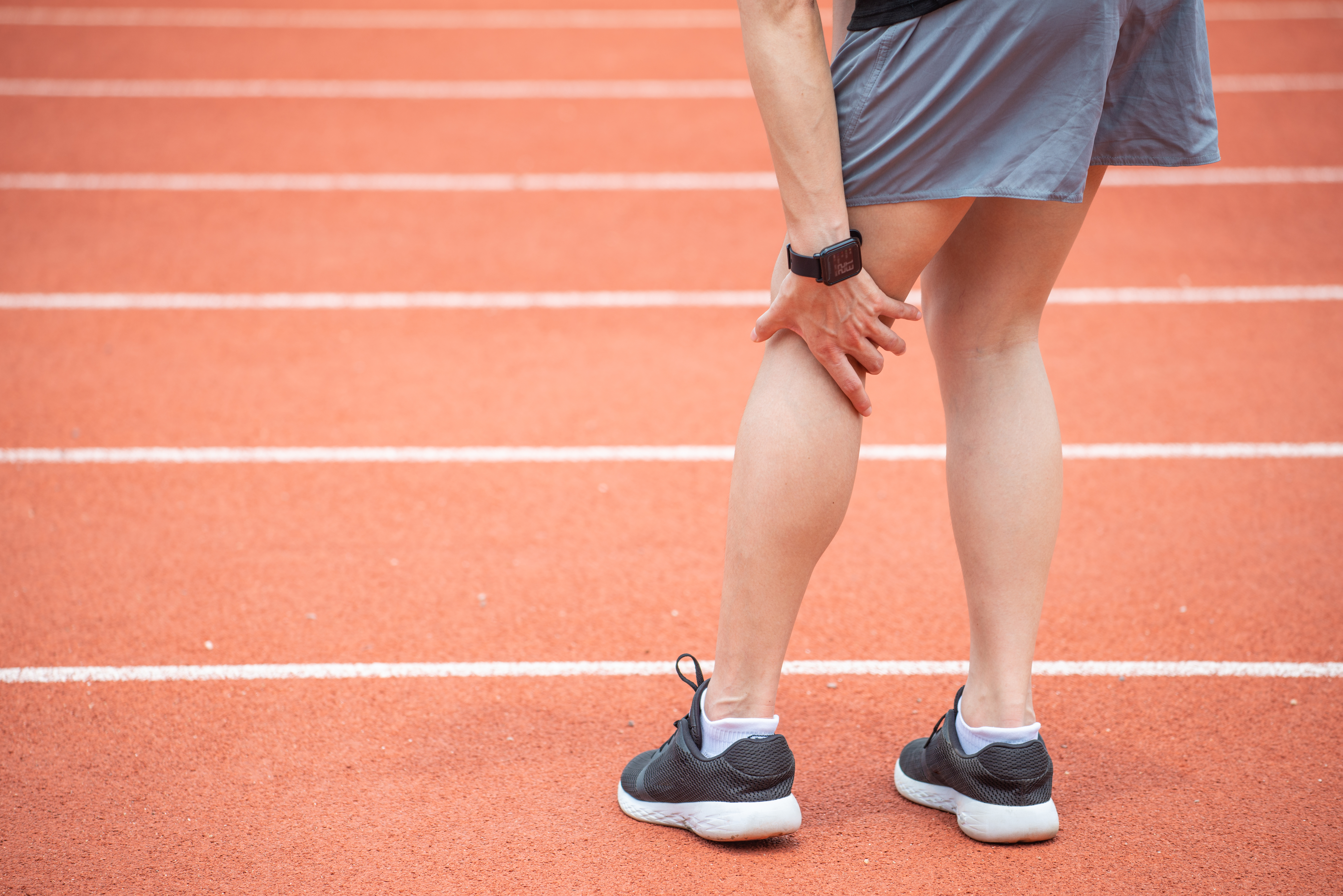 a man on a track grabs at the back of his leg in pain