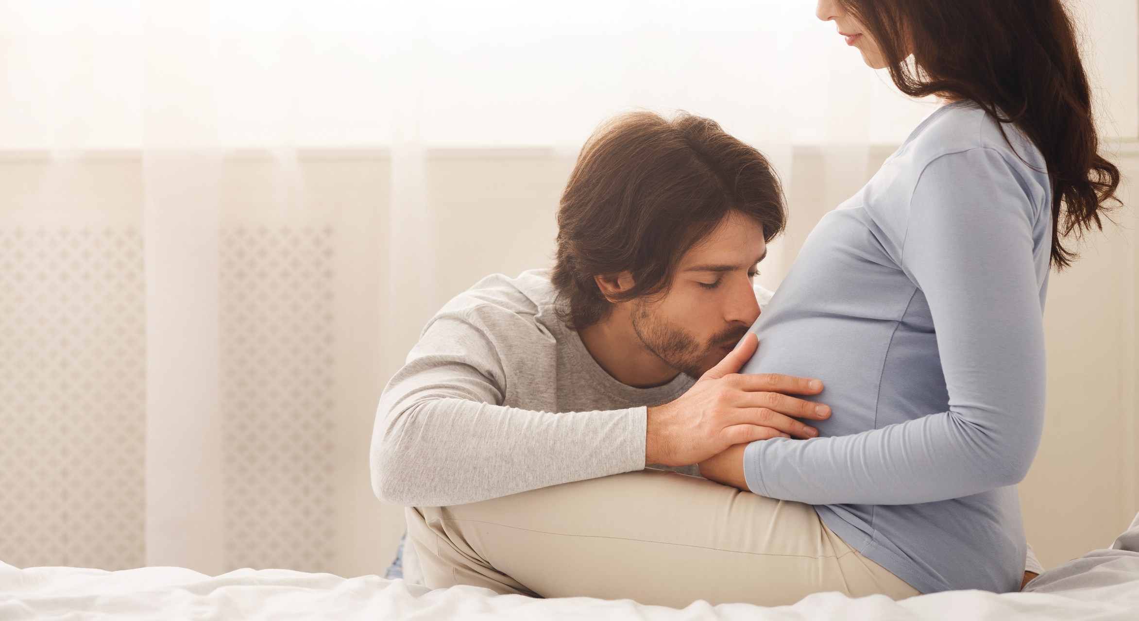 a man kisses a woman's pregnant belly