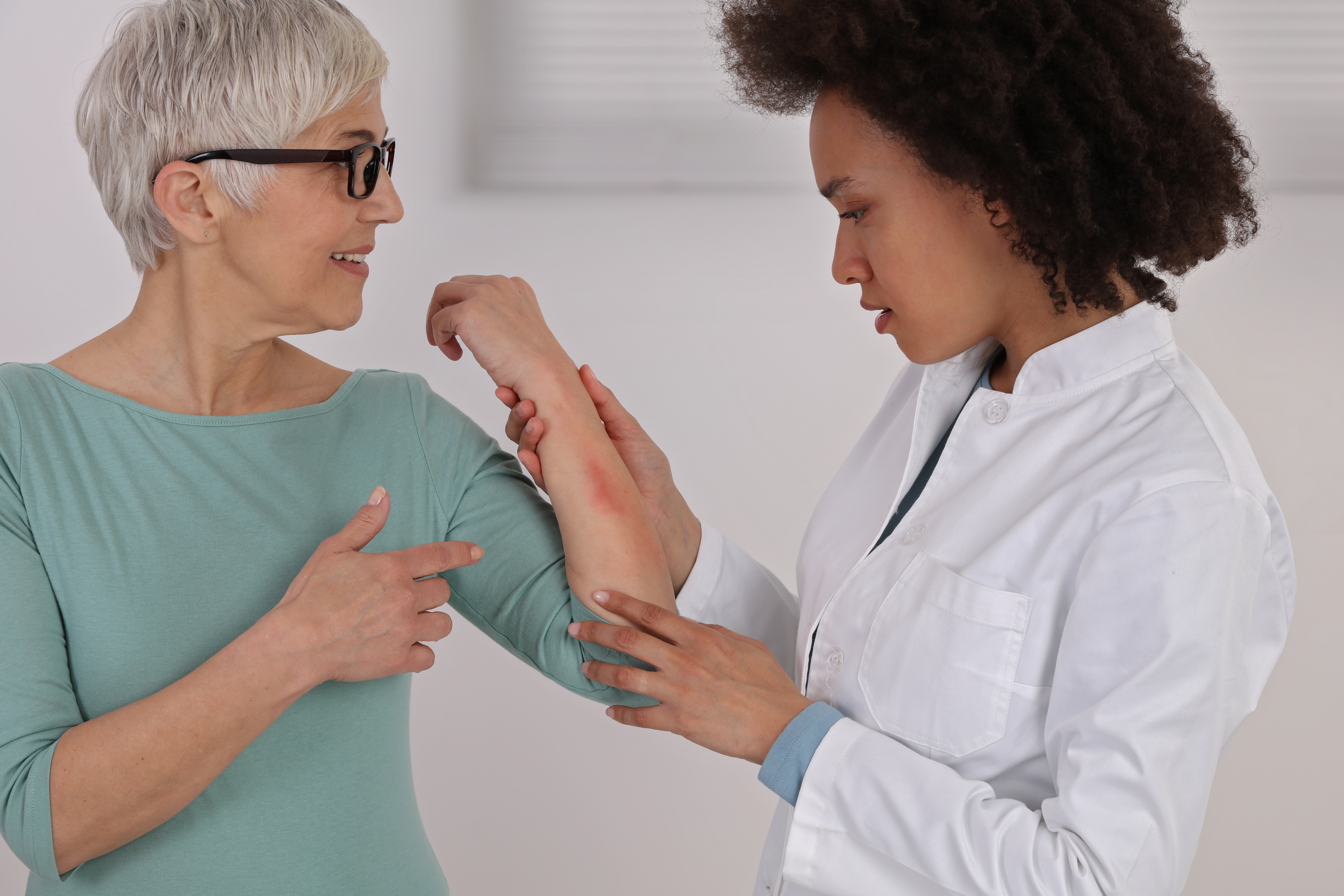 a doctor inspects the skin rash on a patient's arm