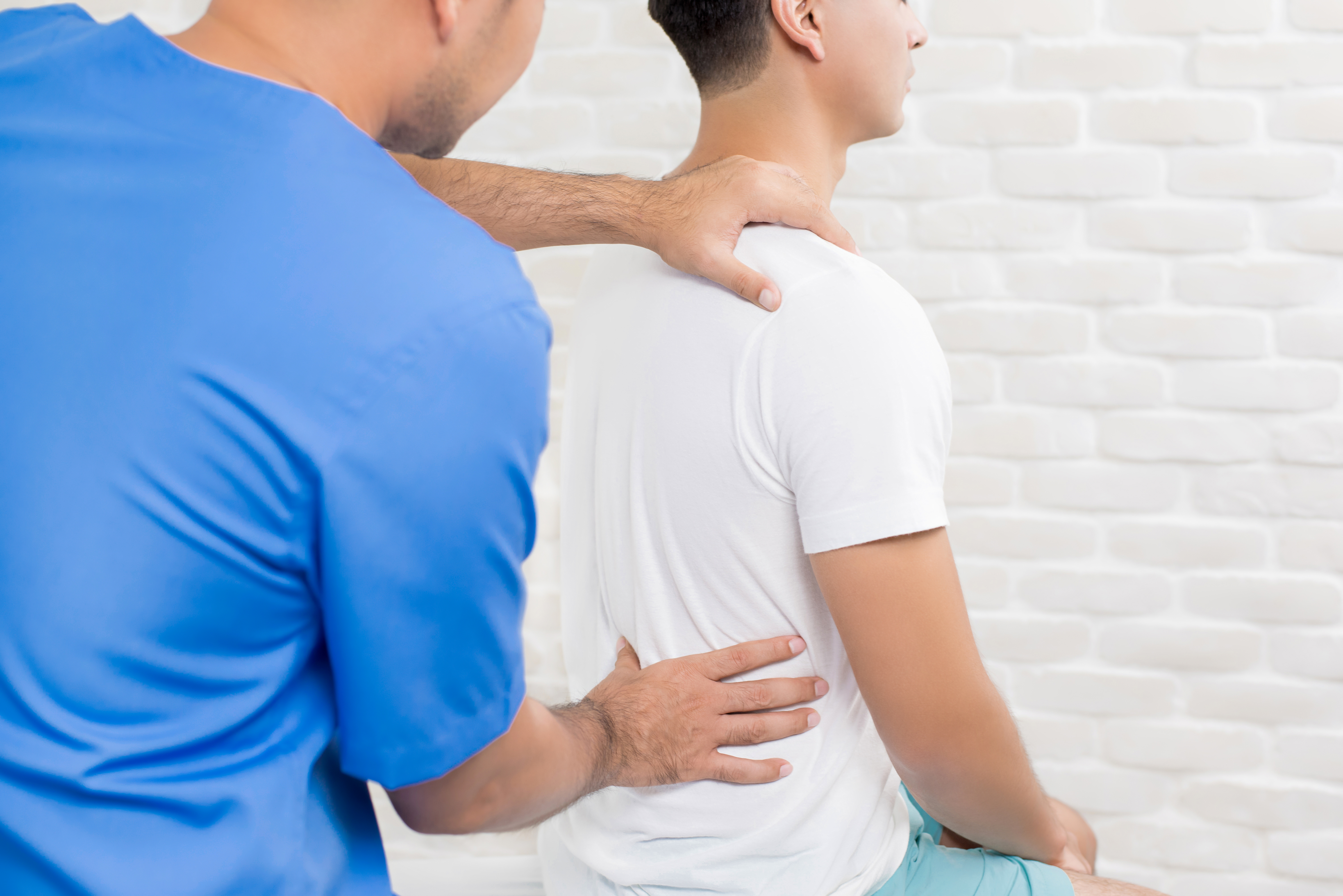 A physical therapist works with a patient and stretching their back