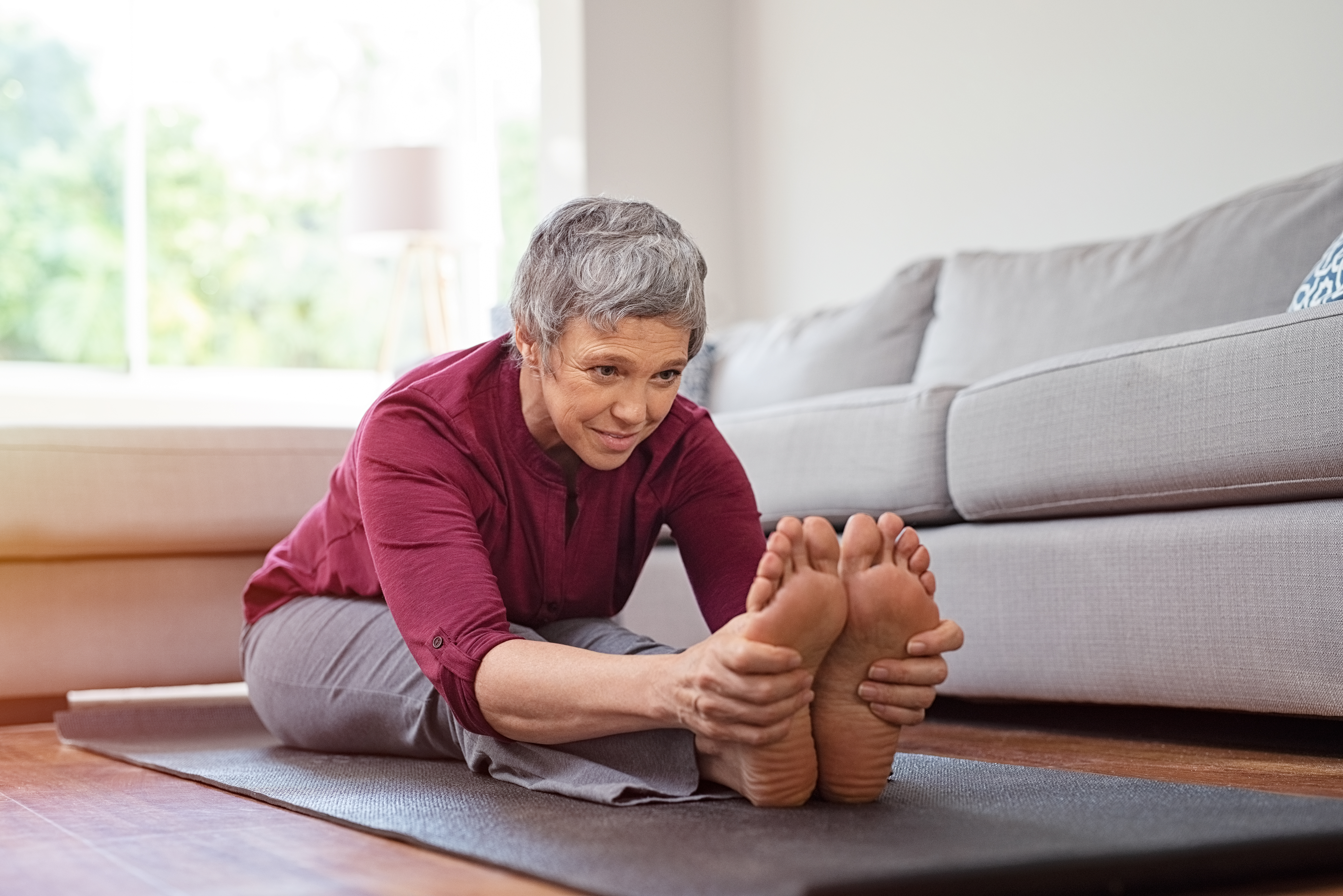 A woman stretches her legs on a yoga mat