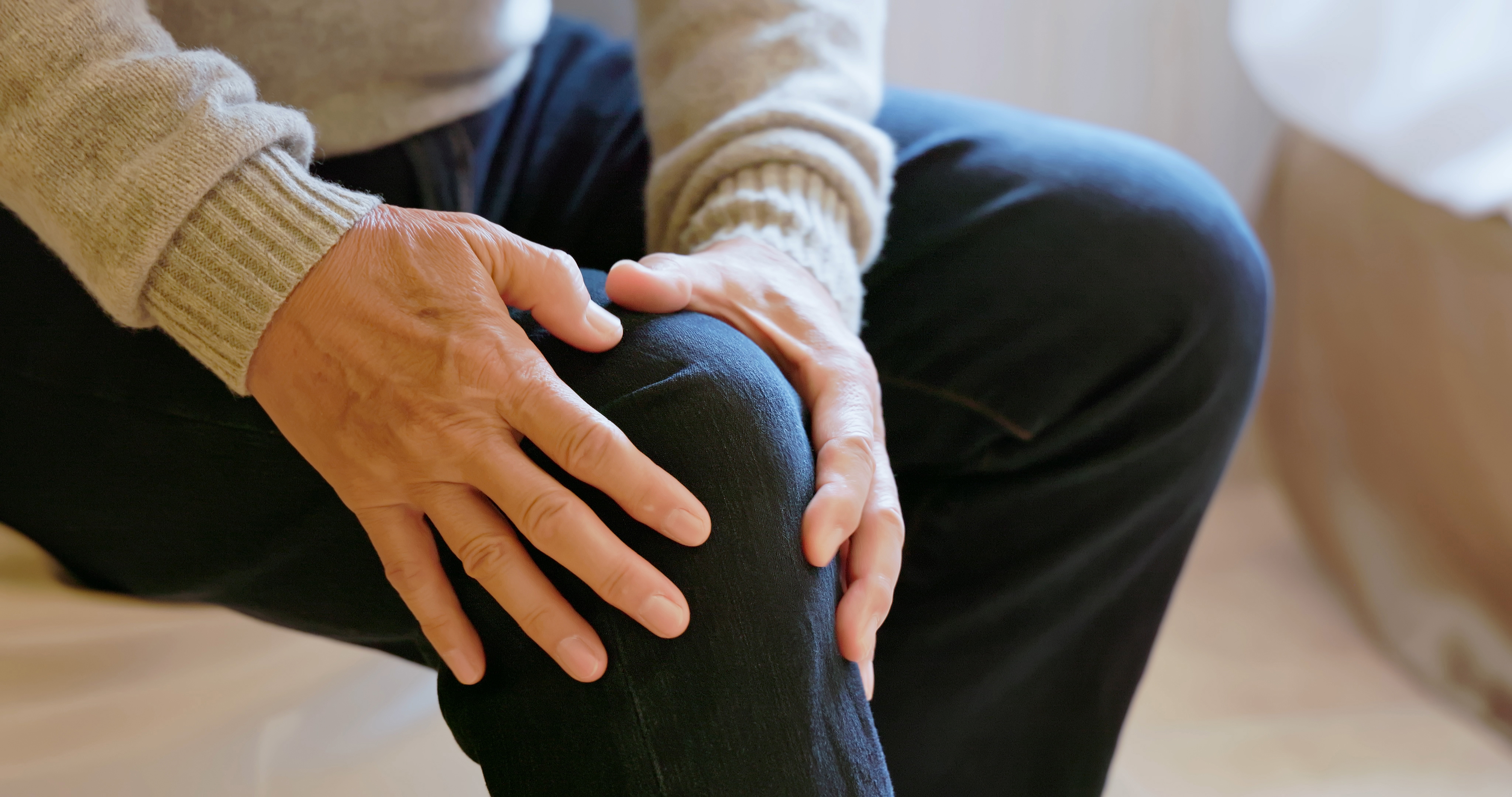 person's hands are shown gripping at their leg in pain