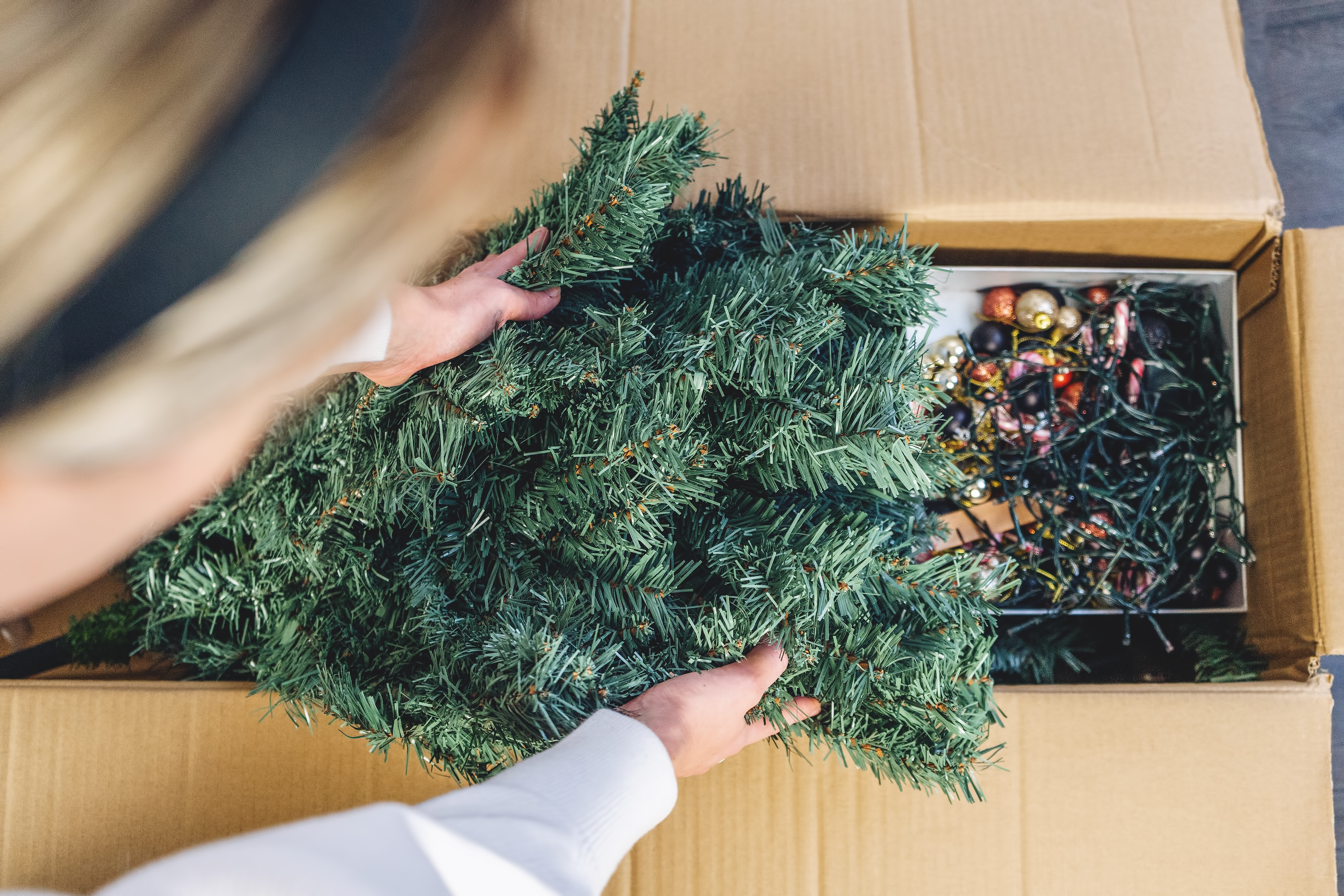 a woman boxes up and stores Christmas decorations