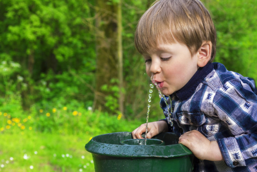little boy drinking from water fountain